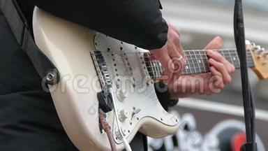 一个男人用白色的身体弹奏电吉他弦。 慢动作。